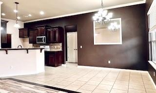 kitchen featuring decorative light fixtures, recessed lighting, stainless steel microwave, an inviting chandelier, and a kitchen bar