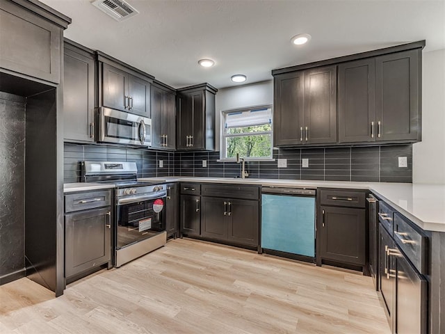 kitchen with a sink, visible vents, light wood-type flooring, and appliances with stainless steel finishes