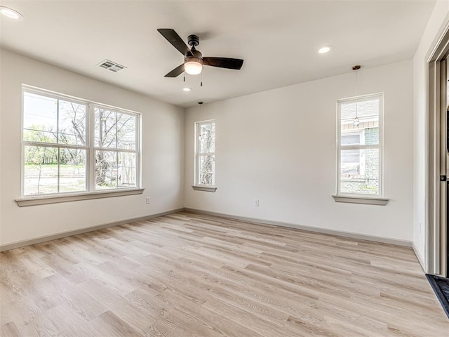 empty room with visible vents, light wood-type flooring, plenty of natural light, and a ceiling fan