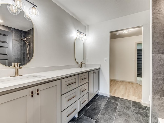 full bath featuring tiled shower, double vanity, visible vents, and a sink