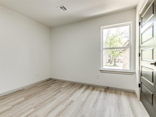 spare room with light wood-type flooring, baseboards, and visible vents