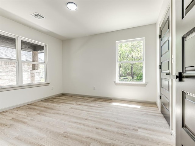 unfurnished room featuring visible vents, baseboards, light wood-type flooring, and plenty of natural light