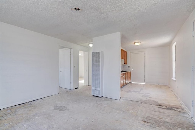 unfurnished living room with a textured ceiling and baseboards