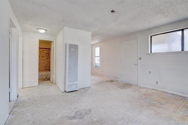 spare room featuring a heating unit and a textured ceiling