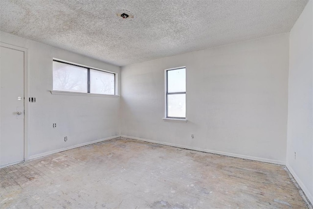 unfurnished room with a textured ceiling and baseboards