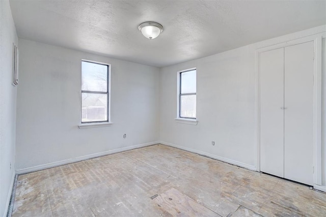 unfurnished bedroom with a textured ceiling and baseboards