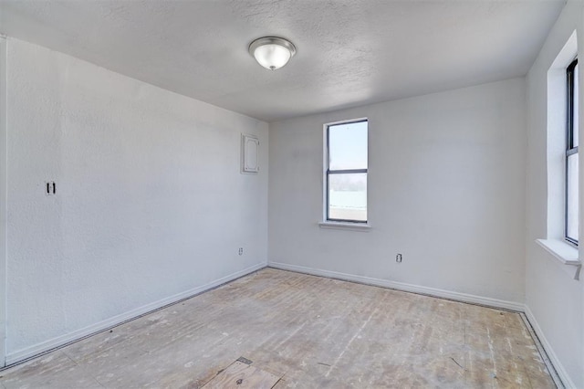 unfurnished room with a textured ceiling and baseboards