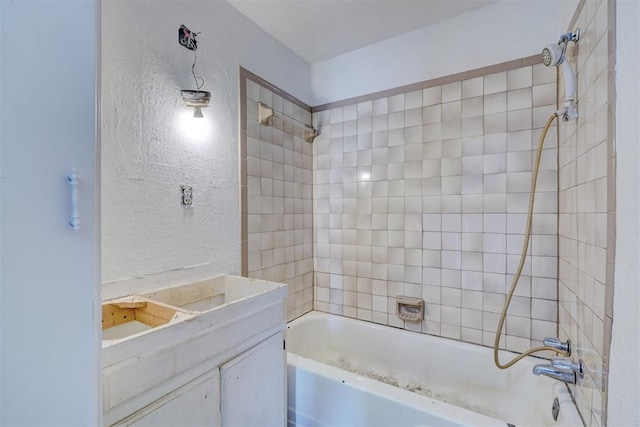 full bath with a textured wall, shower / bath combination, and vanity