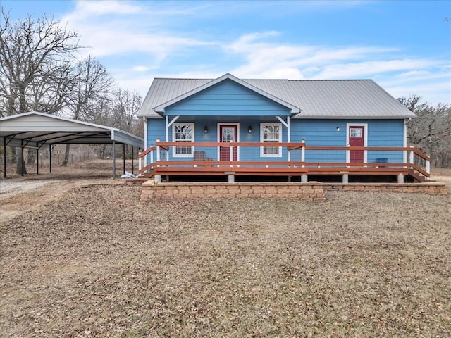 view of front facade with dirt driveway, metal roof, and a carport