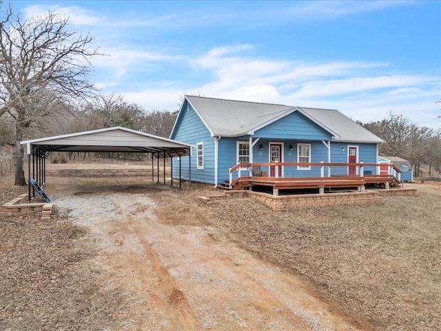 view of front of home featuring driveway, a deck, metal roof, and a detached carport