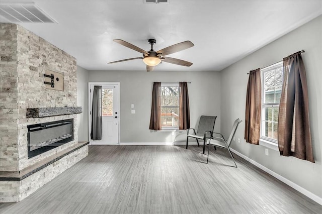 unfurnished room with a fireplace, visible vents, a wealth of natural light, and wood finished floors