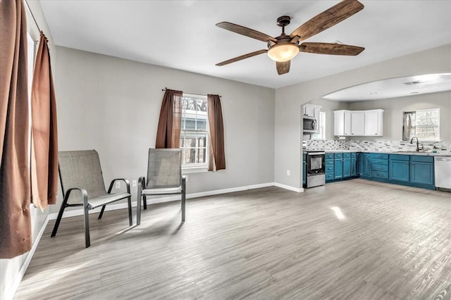 unfurnished room with ceiling fan, a sink, visible vents, baseboards, and light wood-style floors