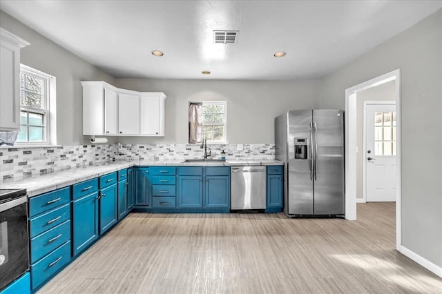 kitchen with blue cabinetry, visible vents, appliances with stainless steel finishes, white cabinets, and a sink