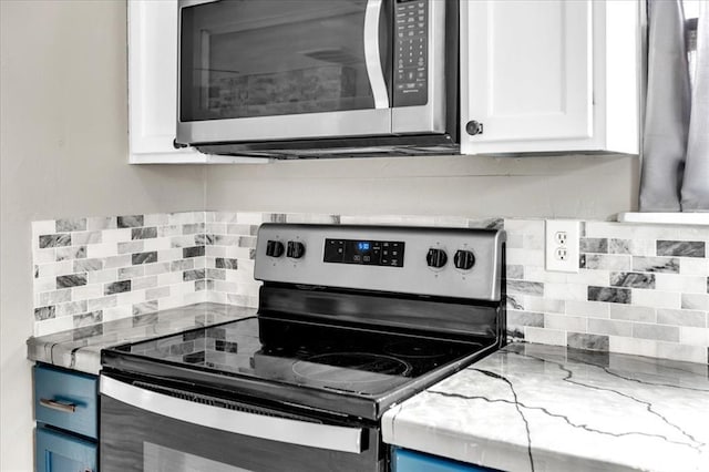 kitchen with blue cabinets, appliances with stainless steel finishes, white cabinets, and light stone counters