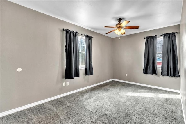 carpeted empty room featuring baseboards and a ceiling fan