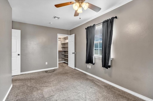 unfurnished bedroom with carpet floors, a spacious closet, visible vents, and baseboards