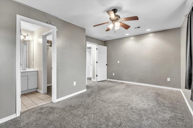 unfurnished bedroom with baseboards, visible vents, connected bathroom, and light colored carpet