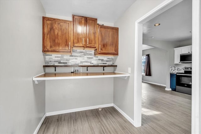 kitchen featuring light countertops, appliances with stainless steel finishes, brown cabinetry, and baseboards