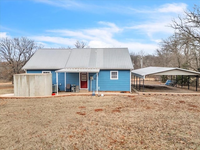 back of house featuring central AC unit, metal roof, a lawn, and a detached carport