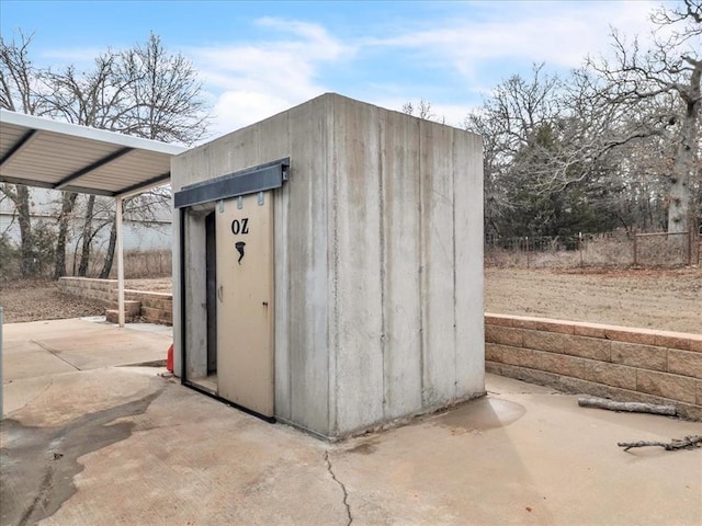 view of outbuilding featuring a carport and fence