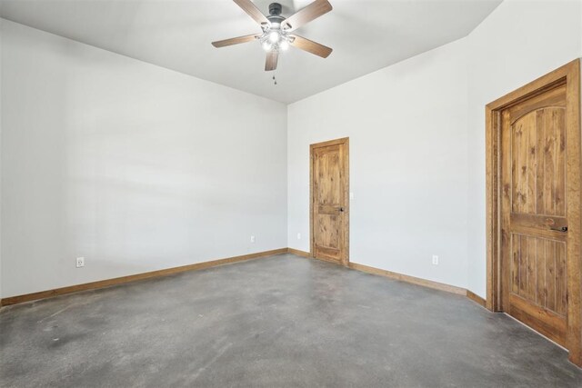 unfurnished room featuring concrete flooring, ceiling fan, and baseboards