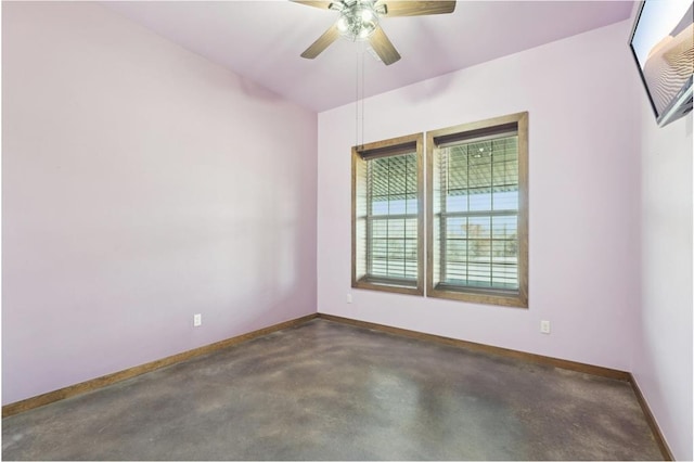 empty room featuring concrete floors, a ceiling fan, and baseboards