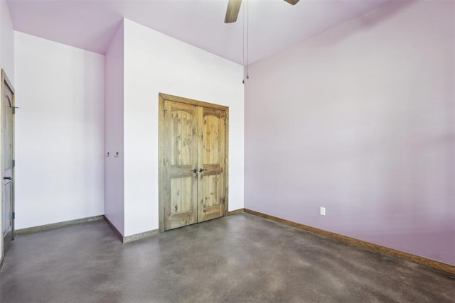 unfurnished bedroom with finished concrete floors, baseboards, and a ceiling fan