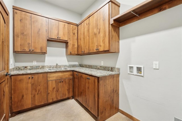 kitchen featuring brown cabinets, a sink, baseboards, and light stone countertops