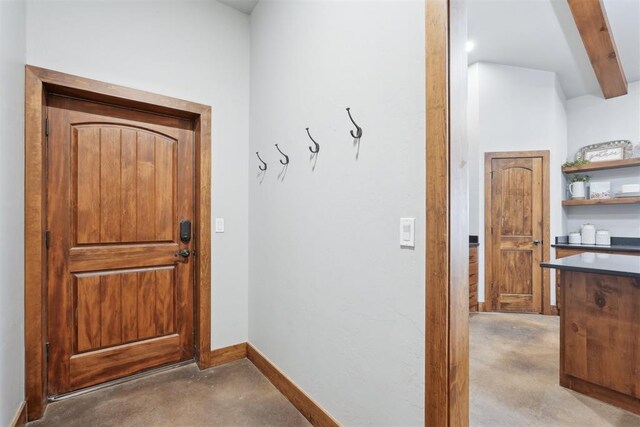 doorway to outside featuring concrete floors, baseboards, and beamed ceiling