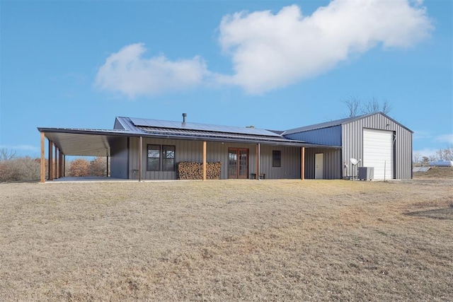 back of property with cooling unit, a yard, roof mounted solar panels, a carport, and board and batten siding