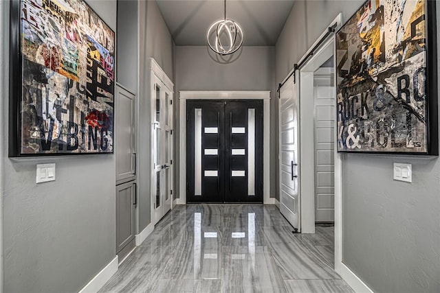 entryway featuring a notable chandelier, baseboards, and a barn door