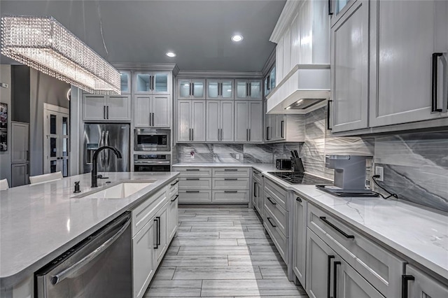 kitchen featuring tasteful backsplash, light stone counters, recessed lighting, stainless steel appliances, and a sink