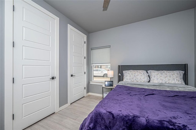 bedroom with a ceiling fan, wood finished floors, and baseboards