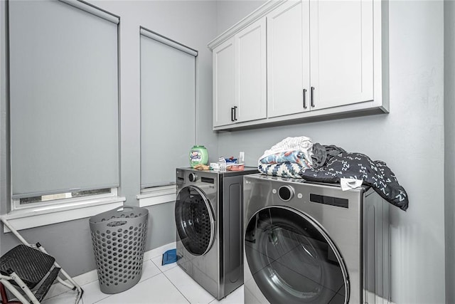 clothes washing area featuring tile patterned floors, cabinet space, baseboards, and washing machine and clothes dryer