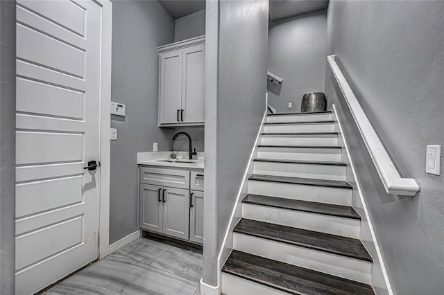 stairway featuring marble finish floor, baseboards, and a textured wall