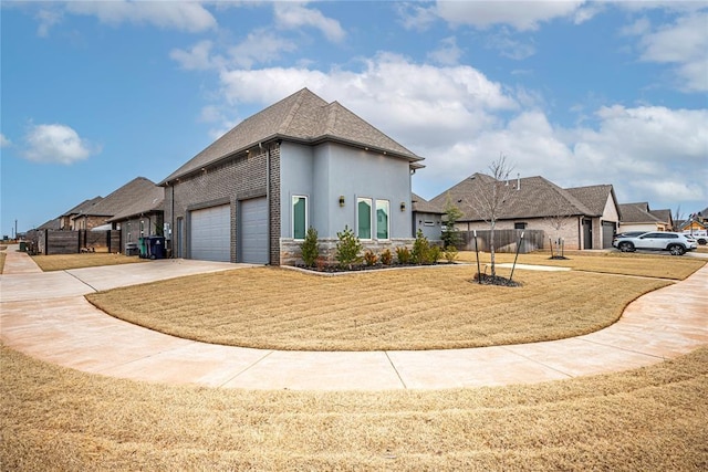 view of front of home with stucco siding, driveway, fence, a yard, and an attached garage