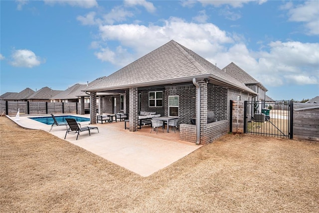 back of property with a gate, a fenced backyard, outdoor lounge area, brick siding, and a patio area