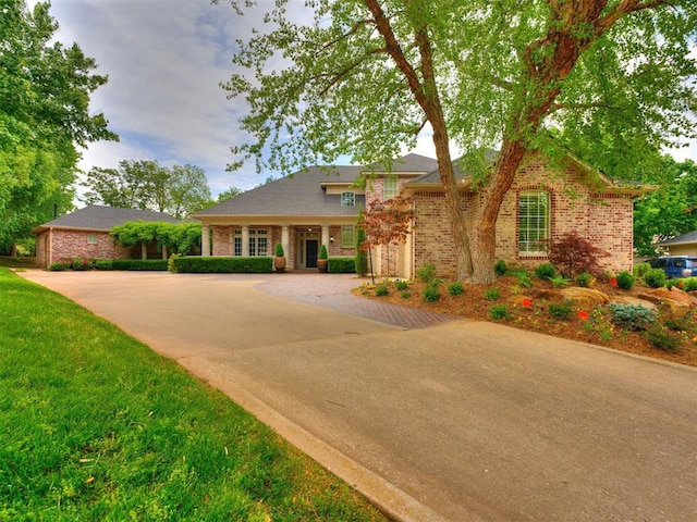 view of front facade featuring a front yard, brick siding, and driveway