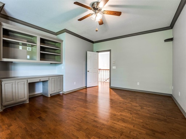 interior space with crown molding, ceiling fan, baseboards, built in study area, and dark wood-style flooring