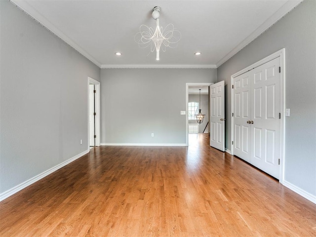 unfurnished room featuring light wood-style floors, an inviting chandelier, and crown molding