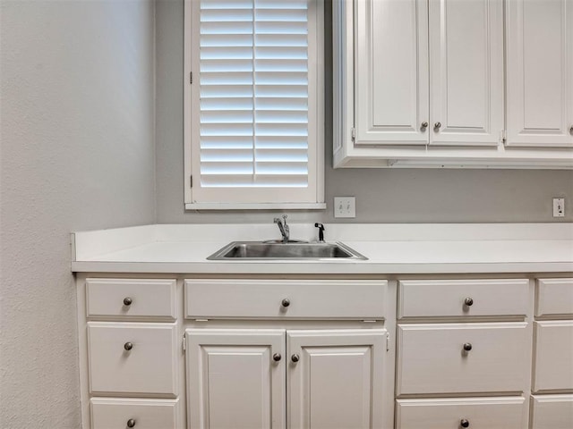 kitchen with white cabinetry, light countertops, and a sink