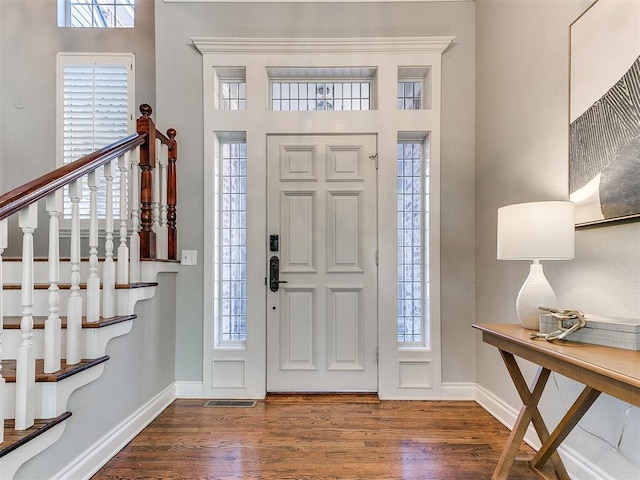 entryway with visible vents, stairway, baseboards, and wood finished floors