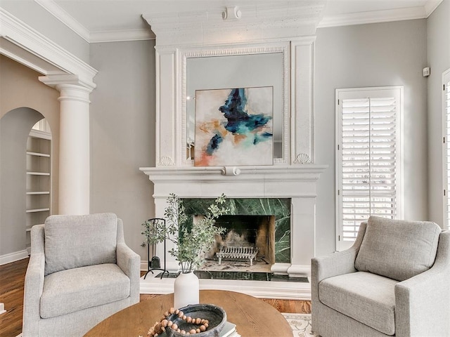 sitting room featuring built in features, a premium fireplace, wood finished floors, and ornamental molding