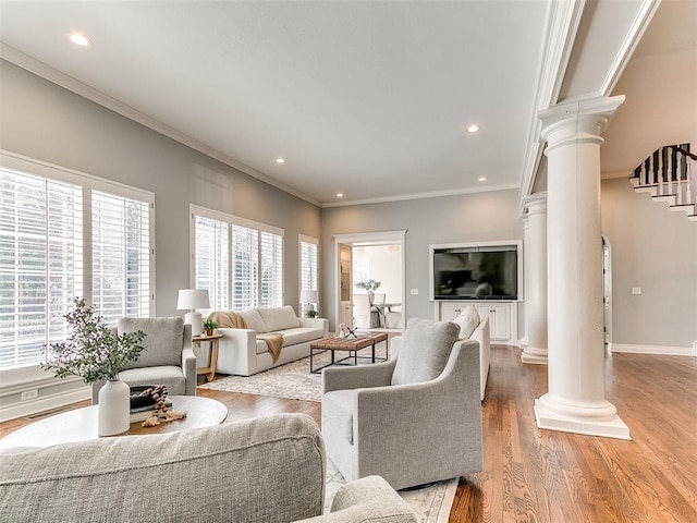 living area with crown molding, light wood finished floors, decorative columns, baseboards, and stairs