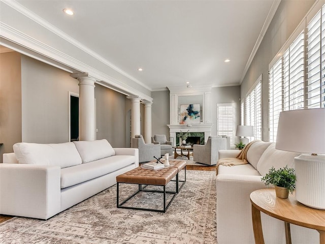 living room featuring crown molding, a large fireplace, decorative columns, recessed lighting, and wood finished floors