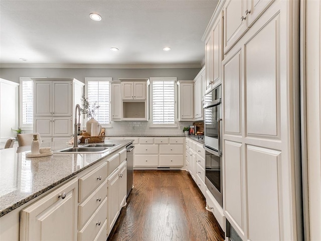 kitchen with light stone counters, dark wood-style flooring, ornamental molding, a sink, and tasteful backsplash