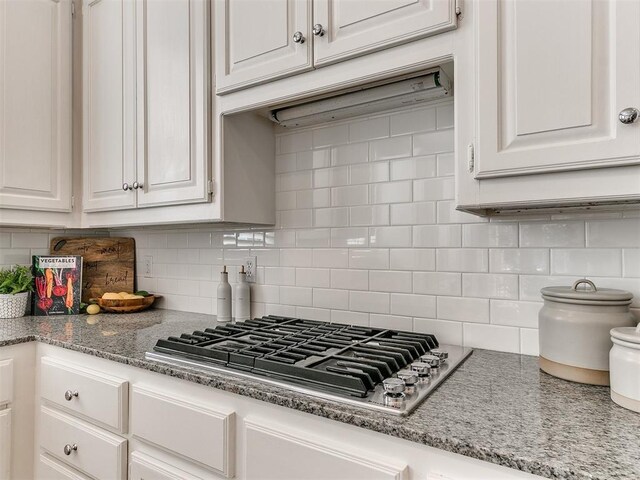 kitchen featuring light stone counters, backsplash, white cabinets, and stainless steel gas cooktop