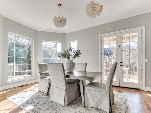 dining space featuring crown molding, baseboards, french doors, an inviting chandelier, and light wood-style floors