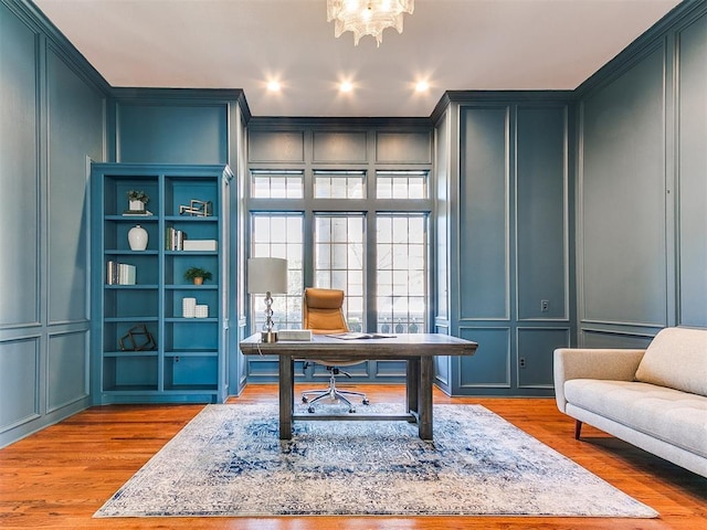 home office featuring crown molding, a chandelier, recessed lighting, wood finished floors, and a decorative wall