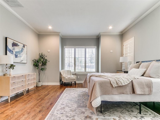 bedroom featuring ornamental molding, wood finished floors, visible vents, and baseboards